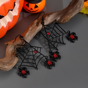 Macro shot of spider web earrings with red rhinestones on festive pumpkin background