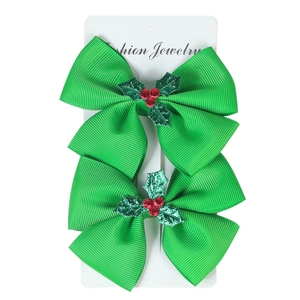 Set of two green Christmas hair bow clips with holly berry sequins on white background