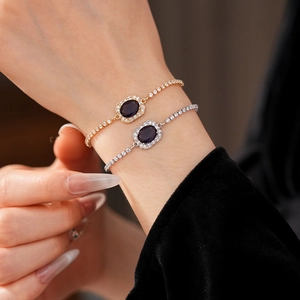 Close-up of zircon drawstring bracelets in gold and silver with oval purple gemstones