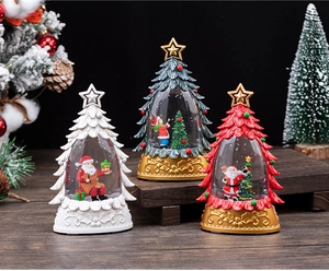 Close-up of three festive Christmas tree snow globes with gold bases on a wooden surface