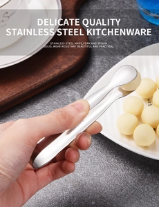 Detail of hand holding stainless steel sugar tongs picking up food from a white plate