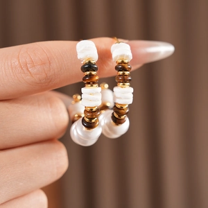 Detalle de pendientes de aro en C con cuentas de ojo de tigre y perlas de estilo retro