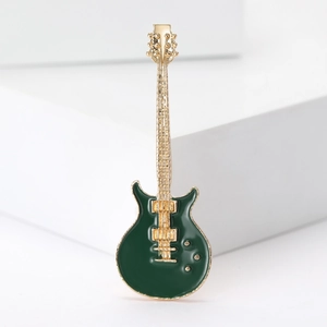 Fashionable guitar brooch with green enamel and gold finish on white background