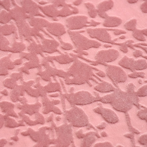 Gros plan sur un tissu en maille floquée rose avec une texture florale gaufrée