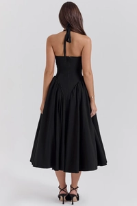 Detail view of the open-back design and pleated skirt of this black halter maxi dress