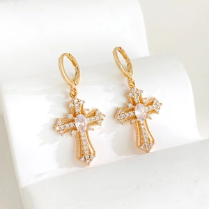 Elegant gold-plated cross drop earrings with pavé crystals on a minimalist display