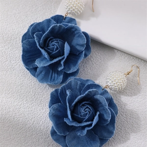 Detailed close-up of blue denim camellia earrings with elegant pearl beaded accents