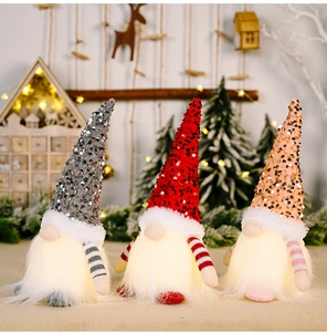Three glowing Christmas gnomes with sequined hats and warm LED lights on a wooden table