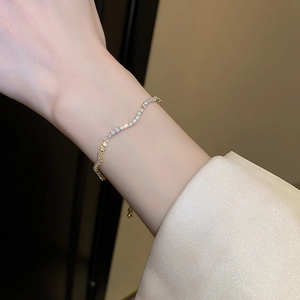 Detail of gold wave bracelet with pave cubic zirconia worn on a woman's wrist