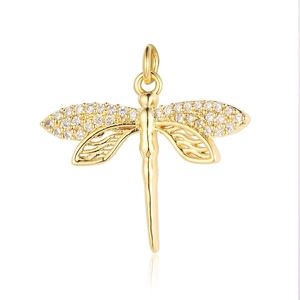 Close-up of golden dragonfly pendant with sparkling zircon wings on white background