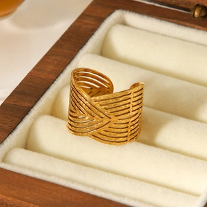 Anello di lusso in acciaio inossidabile dorato con linee intrecciate su portagioie in legno