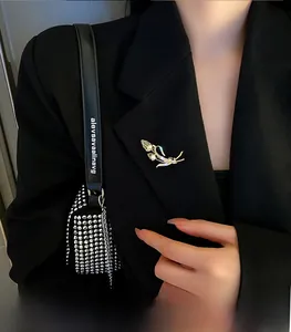 Gros plan d'une broche épi dorée avec cristaux bleus sur une veste de tailleur noire