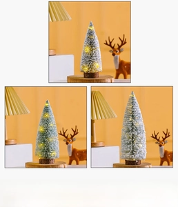 Close-up of mini flocked Christmas tree with warm LED lights and a wooden base on desk