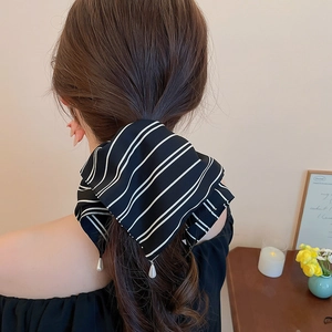 Détail de l'élastique à cheveux rayé noir et blanc avec élégantes perles blanches en gouttes