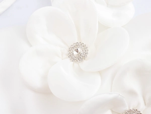 Makro-Detail der weißen Satin-3D-Blume mit funkelnder Strass-Mitte für Kleider