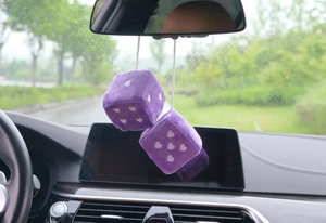 Detail of purple plush dice car ornaments with white heart patterns hanging on a rearview mirror