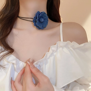 Close-up of blue denim 3D flower choker with black ribbon on model neck