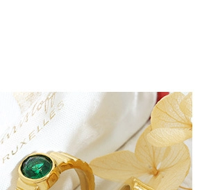 Macro shot of a vintage gold ring with a round green gemstone on a soft fabric background