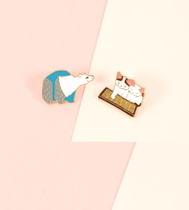 Close-up of cute cartoon enamel pins featuring a polar bear and kittens in a basket