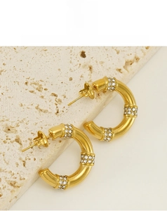 Détail des boucles d'oreilles bambou dorées 18K avec des cristaux étincelants