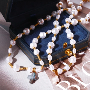 Collier de perles baroques avec pendentif croix sur boîte à bijoux en velours bleu
