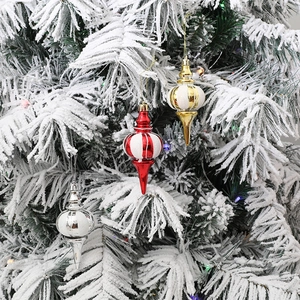 Glitzernde Weihnachts-Spindelanhänger in Rot, Gold und Silber an einem schneebedeckten Baum