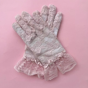 Detail of pink floral lace gloves featuring elegant ruffled cuffs and intricate patterns