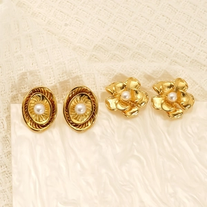 Elegant gold flower and oval stud earrings with pearl centers on soft knit fabric