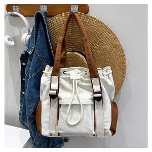 Detailed view of canvas tote bag with drawstring closure and brown strap on a wall hook
