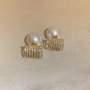 Detail of geometric pearl earrings with shimmering zirconia on golden metal base