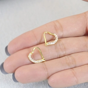 Close-up of gold S925 silver heart stud earrings with cubic zirconia on a model