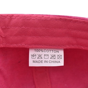 Detail of internal care label on pink washed cotton hat showing 100% cotton fabric and washing symbols