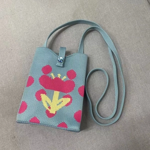 Detail shot of blue knitted phone bag featuring pink floral patterns and button closure