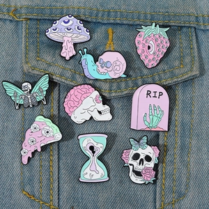 Collection of gothic enamel pins featuring skull butterfly and mushroom designs on denim