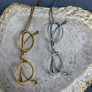 Minimalist gold and silver eye pendant necklaces with matte finish on ceramic tray