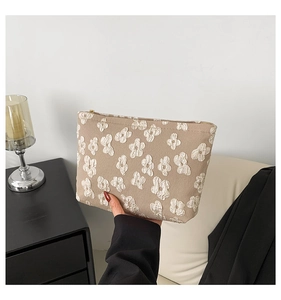 Detailed macro view of beige floral embossed fabric and golden zipper on this small pouch