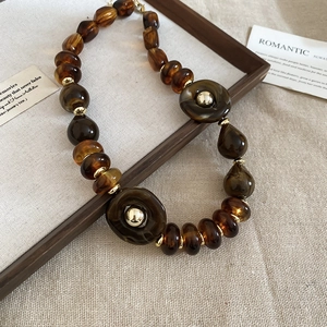 Detailed close-up of amber acrylic beads and gold spacers on a textured linen background