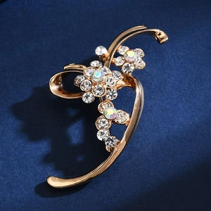Detail shot of golden floral brooch with sparkling rhinestones on blue fabric