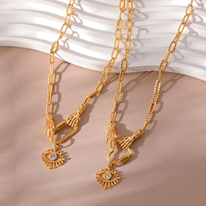 Gold Evil Eye necklace with hand-shaped clasp and crystal pendant on beige leather