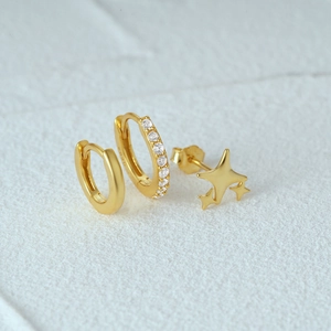 Detailed set of three gold earrings with stars and zircon crystals on stone