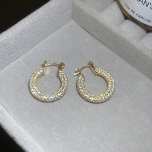 Detail of gold-plated U-shaped earrings with pavé cubic zirconia on grey velvet