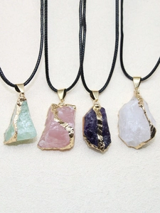 Détail de quatre pendentifs en pierre naturelle irrégulière avec placage or sur fond beige