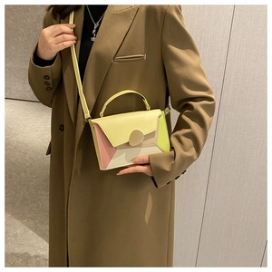 Close-up of color-block crossbody bag styled with a brown coat for chic commute