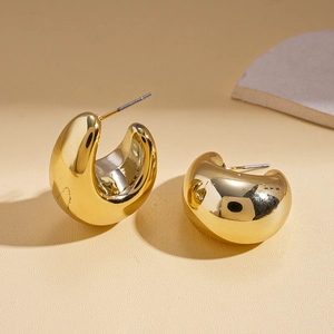 Close-up of polished golden C-shape geometric stud earrings with smooth metallic finish