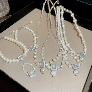 Close-up of pearl jewelry set with square blue opal pendants and silver hardware
