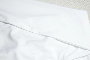 Detailed close-up of white high-elastic fabric texture and double-needle edge stitching