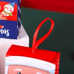 Christmas gift box with red ribbon handle featuring festive red and blue holiday designs