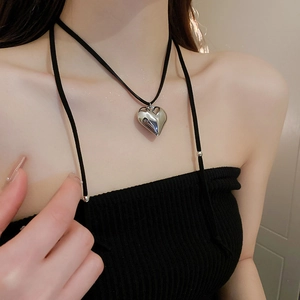 Close-up of a 3D silver heart pendant necklace on a minimalist black leather cord