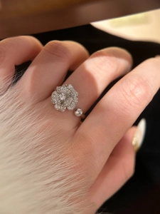 Detailed close-up of a sparkling zircon flower ring worn on finger in elegant style