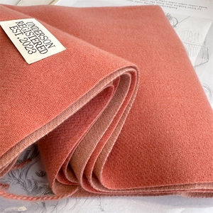 Close-up of orange cashmere blend scarf fabric texture with a minimalist white brand label